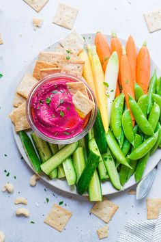 a plate with crackers, vegetables and dip on it