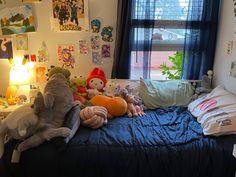 several stuffed animals sit on top of a bed in front of a window with blue curtains