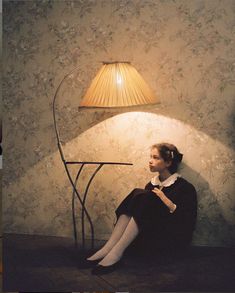 a woman sitting on the floor next to a lamp