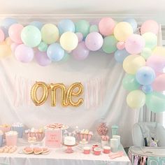 a table topped with balloons and cake next to a sign that says one on it