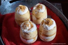 four desserts sitting on top of a red towel in a glass dish with cinnamon crumbs