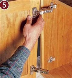 a man is opening the door to his kitchen cabinet with an open latch on it