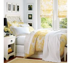 a bedroom with yellow and white bedding and pictures on the window sill above the bed