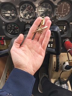 a hand holding a keychain in front of an airplane cockpit