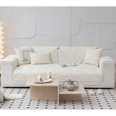 a white couch sitting next to a table on top of a tiled floor