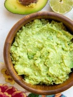 a bowl filled with guacamole next to an avocado