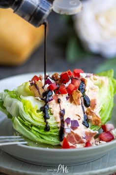 someone is drizzling dressing on a lettuce leaf with bacon and tomatoes