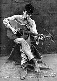 a man sitting on the ground playing a guitar