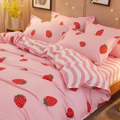 a bed covered in pink and white sheets with strawberries printed on the comforter