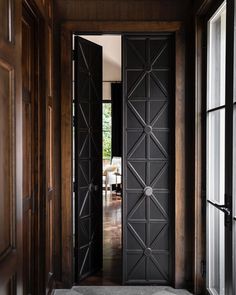 an open door leading into a living room with wood paneled walls and flooring