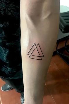 a person with a small tattoo on their arm and leg that has two triangles in it