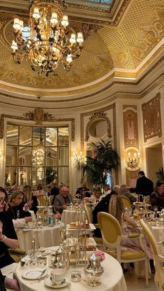 people are sitting at tables in a fancy dining room with chandeliers and white tablecloths