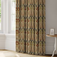 a curtain with an ornate design on it in the corner of a room next to a window