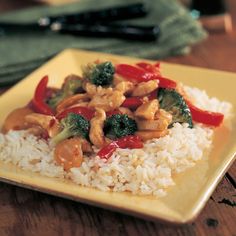 a yellow plate topped with rice and veggies on top of a wooden table