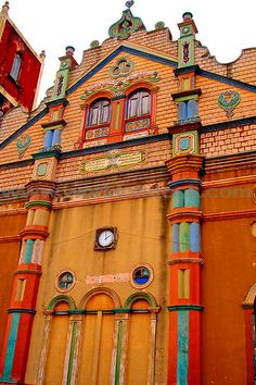 an old building with many windows and colorful trimmings on the front, along with a clock at the top