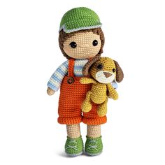 a crocheted doll holding a stuffed animal on a white background with a green hat and orange overalls