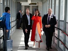 two men and a woman walking down a hallway