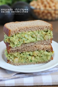 a sandwich with avocado and chickpeas is on a plate next to a fork