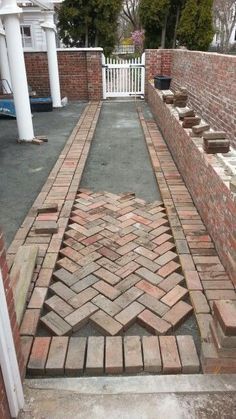 a brick walkway leading up to a white picket fence