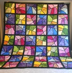 a colorful stained glass quilt hanging on a wall