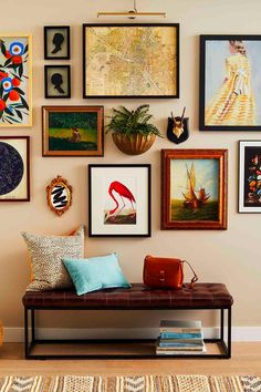 a room with many framed pictures on the wall and a bench in front of it