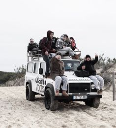 several people sitting on top of an off road vehicle in the middle of sand dunes