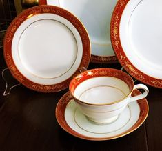 a table topped with plates and cups on top of a wooden table covered in gold trimming