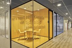 an office with glass walls and chairs in the center, surrounded by wood flooring