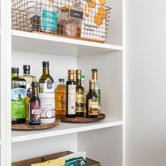 the shelves are filled with different types of bottles and condiments in baskets on them