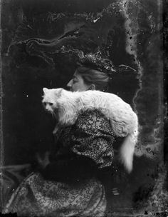 an old black and white photo of a woman holding a cat