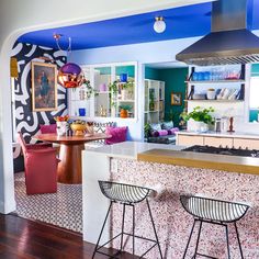 an image of a kitchen setting with blue and white decor on the walls, counter tops and stools