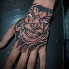 a man's hand with a tattoo on it and a face painted on the palm