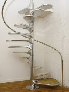 a metal spiral staircase in the corner of a room with wood floors and white walls