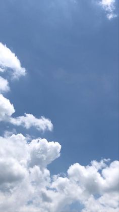 the airplane is flying high in the blue sky with white clouds above it and below