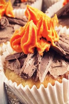 several cupcakes with chocolate frosting and orange icing on a glass plate