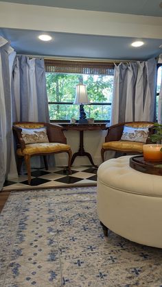 a living room with two chairs and a rug on the floor in front of a window