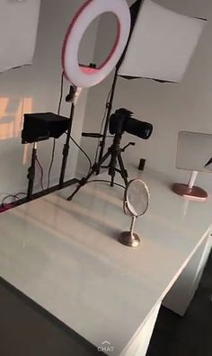 a white table topped with two lights and a camera on top of it next to a lamp