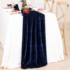 the table is set with two wine glasses and an arrangement of red flowers on it