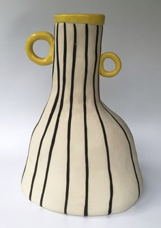 a white and black striped vase with yellow handles