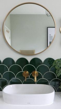 a white sink sitting under a round mirror next to a wall mounted faucet