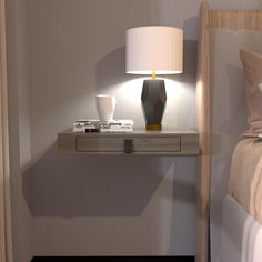 a nightstand with a lamp on top of it next to a bed