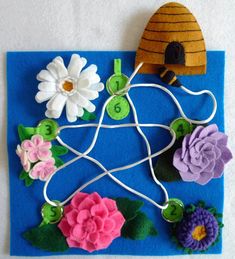 a piece of felt with flowers on it and a birdhouse in the background, sitting on a blue mat