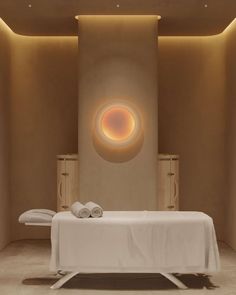 a spa room with a white table and towels on it's legs, in front of a circular light