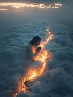 a person kneeling down in the clouds with their hands together and lights shining from them