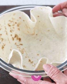 two hands holding a glass bowl filled with food