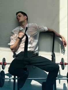 a man sitting on top of a metal bench wearing a tie