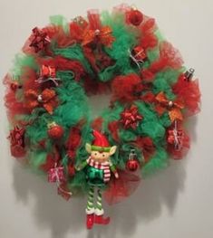 a christmas wreath hanging on the wall with an elf figure attached to it's front