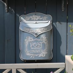 an old post box mounted to the side of a blue building with flowers growing in it