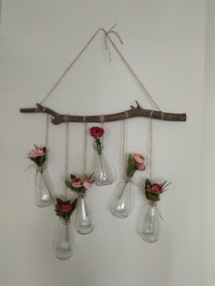 three vases with flowers are hanging from a branch in the shape of a wind chime