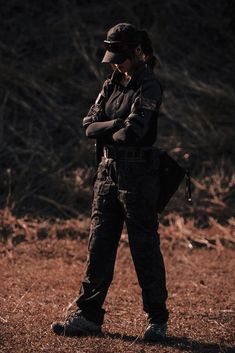 a woman in uniform is standing on the ground with her arms crossed and looking down